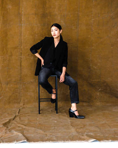 Studio shot of the fit model elegantly seated in the B O R O デニム (BORO DENIM) 'Paint it Black' Tokyo jeans, showcasing their contemporary design and mid-rise, straight-leg silhouette inspired by the Levi's 501 big E