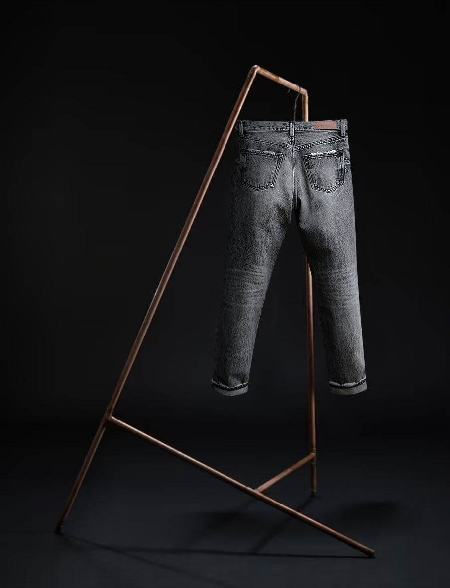 Back view of the B O R O デニム (BORO DENIM) 'Osaka Deep in the Heart' washed black jeans displayed on a rack against a black background. These jeans emphasize the premium Japanese Selvedge Fabric and their unique vintage appeal