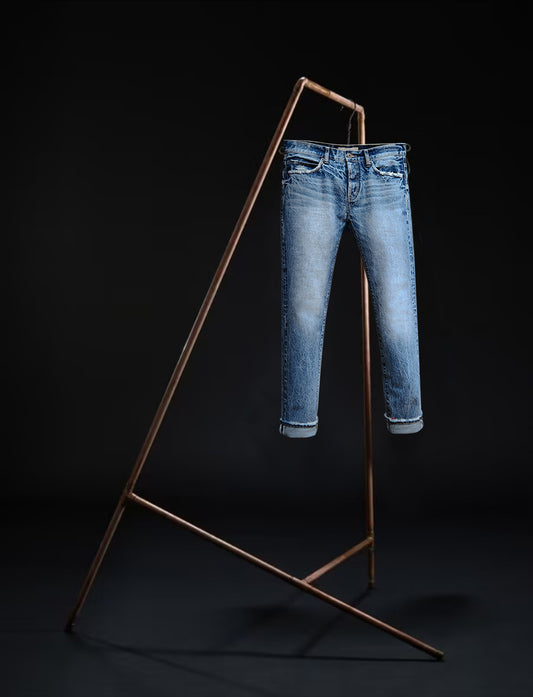 Sapporo jeans by B O R O デニム (BORO DENIM) in 'Gold in the Ceiling' wash hanging on a rack. The design emphasizes the Japanese Selvedge fabric and vintage allure, displayed against a black background showing the front side.