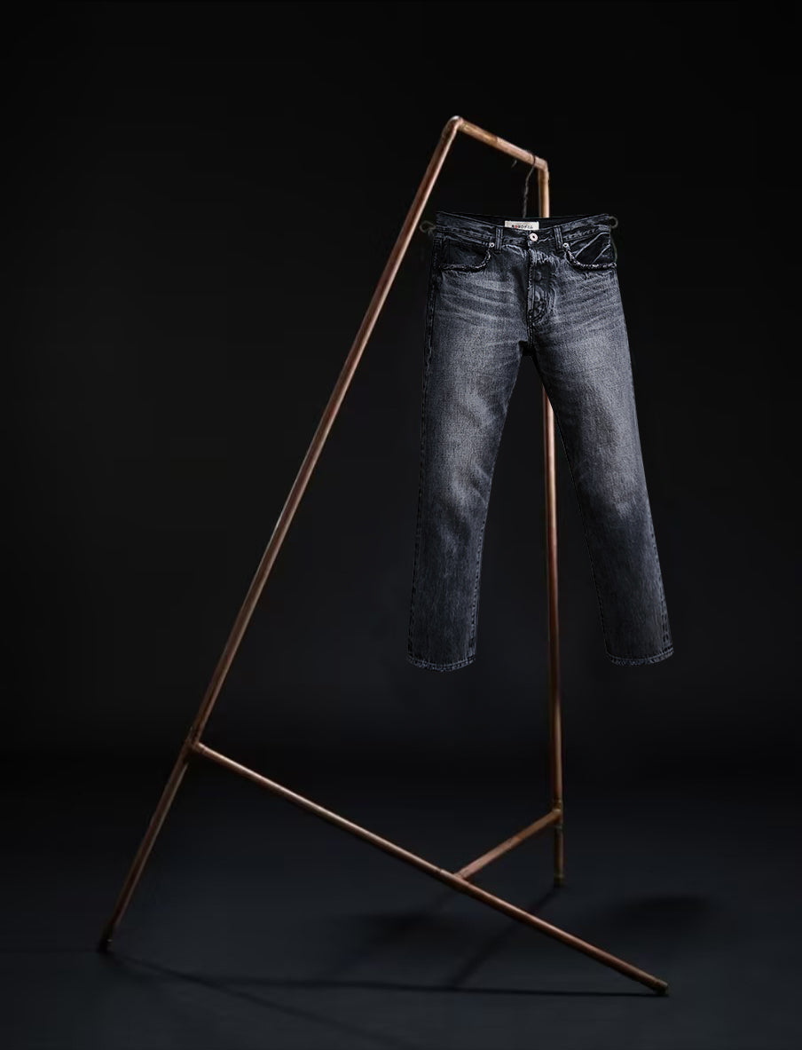 Tokyo jeans by B O R O デニム (BORO DENIM) in the 'Paint it, black' colorway, displayed elegantly on a rack. The back side of the jeans emphasizes the superior Japanese Selvedge fabric and the genuine mid-blue vintage wash, contrasting beautifully with a black backdrop