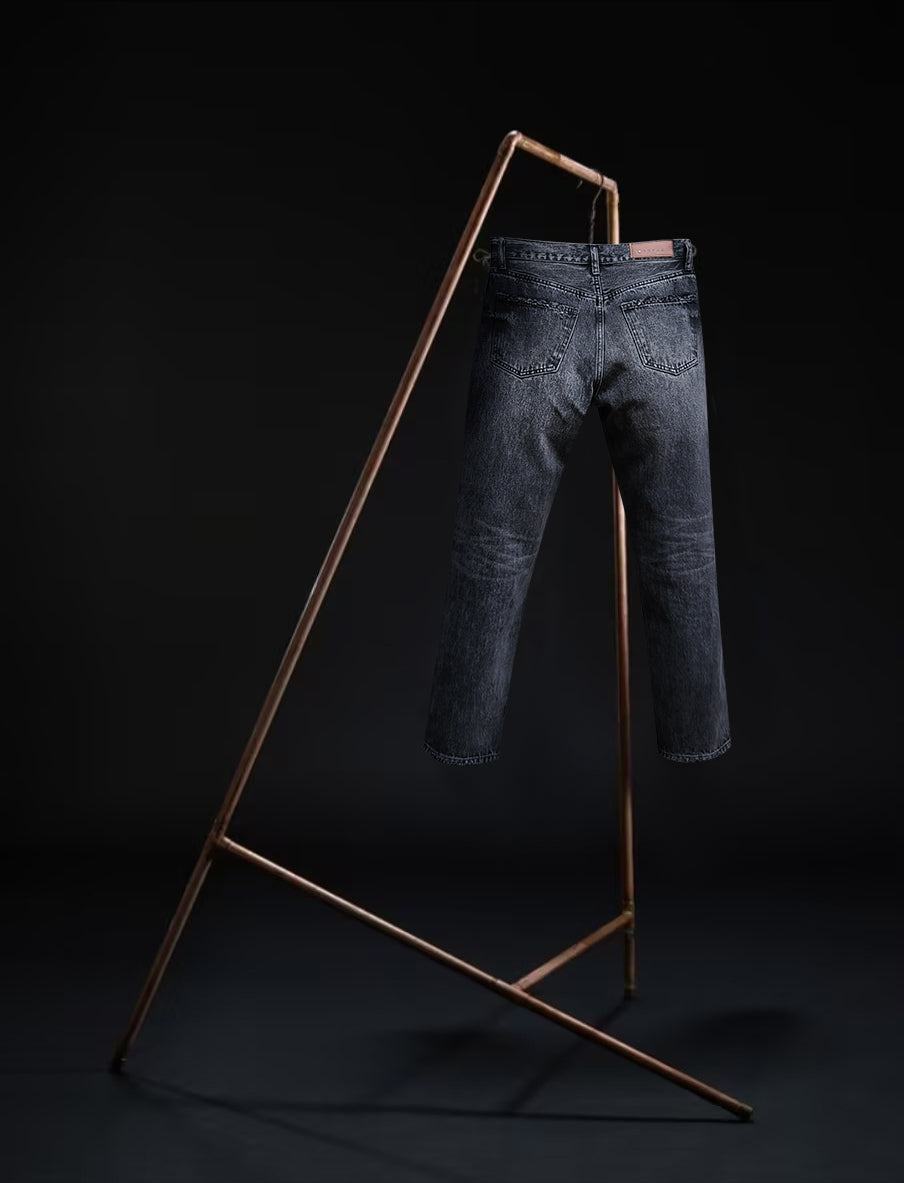 Tokyo jeans by B O R O デニム (BORO DENIM) in the 'Paint it, black' colorway, displayed elegantly on a rack. The back side of the jeans emphasizes the superior Japanese Selvedge fabric and the genuine mid-blue vintage wash, contrasting beautifully with a black backdrop