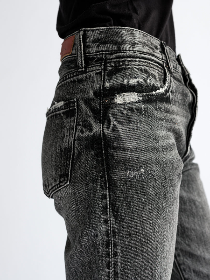 "Close-up view of the B O R O デニム (BORO DENIM) 'Osaka Deep in the Heart' washed black jeans worn by a fit model. The image highlights the pristine Japanese Selvedge fabric and the jeans' authentic vintage wash."