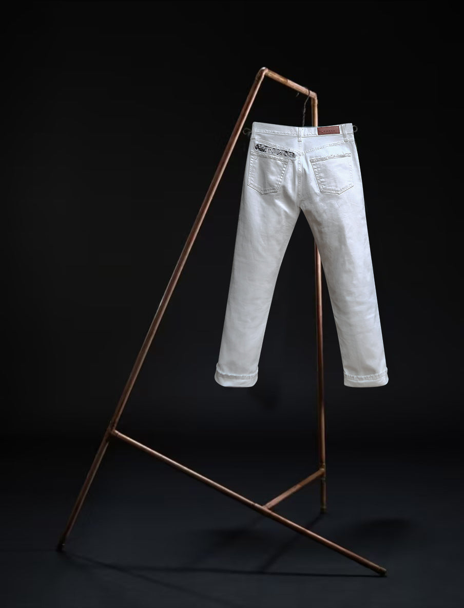 Tokyo jeans by B O R O デニム (BORO DENIM) in the 'Going down south' colorway, displayed elegantly on a rack. The back side of the jeans emphasizes the superior Japanese Selvedge fabric and the genuine off-white vintage wash, contrasting beautifully with a black backdrop.