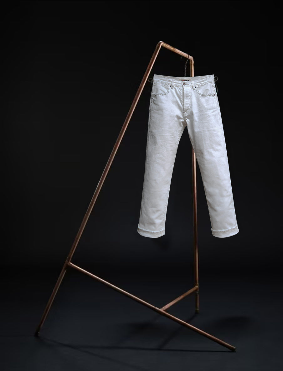 Tokyo jeans by B O R O デニム (BORO DENIM) in the 'Going down south' colorway, displayed elegantly on a rack. The front side of the jeans emphasizes the superior Japanese Selvedge fabric and the genuine off-white vintage wash, contrasting beautifully with a black backdrop.